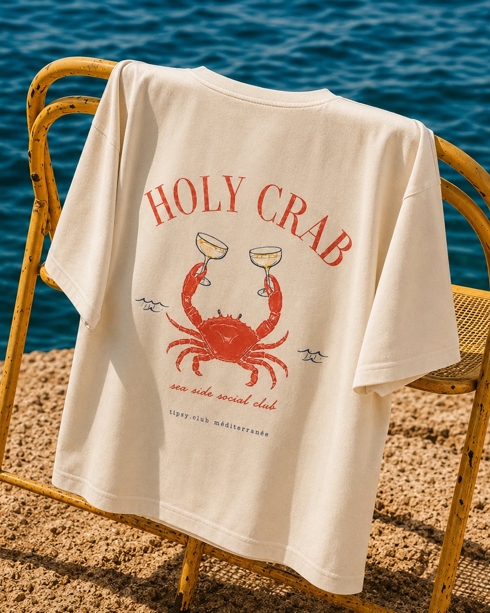 Holy Crab tee on a chair by the sea, back print visible