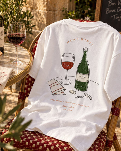More Wine tee on a café chair, back print of a green wine bottle and a glass of red
